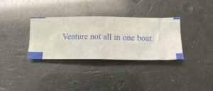 Image of a fortune cookie paper quote 'Venture not all in one boat.'